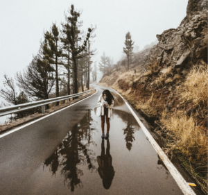 girl walking alone on wet road in mountains